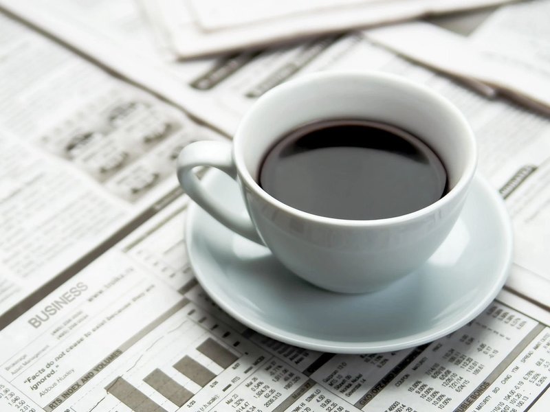 A Cup Of Coffee On A Pile Of Assorted Paper Documents